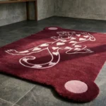 Wide perspective view of the Panther of Hearts rug bathed in stark natural sunlight and sharp shadows, placed on a dark stone tile floor in a modern room with a minimalist black and wood bench.