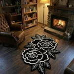 Perspective view of the Petal Duet black and white floral rug styled in a living room on a dark wood floor near a classic black fireplace, a potted plant, and a light grey sofa.