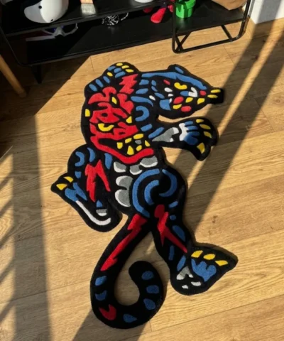 Angled perspective view of the vibrant Phantom Panther neo-traditional tattoo rug, perfectly showcasing its dynamic shape, sharp claws, and striking red and blue color palette on a warm hardwood floor.