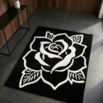 Perspective view of the Phantom Rose black and white rug styled in a modern entryway with dark slate tile flooring, wood paneling, and a minimalist black console table, bathed in a beam of natural sunlight.