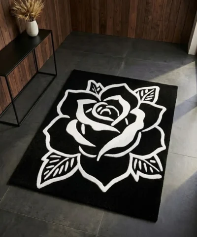 Perspective view of the Phantom Rose black and white rug styled in a modern entryway with dark slate tile flooring, wood paneling, and a minimalist black console table, bathed in a beam of natural sunlight.