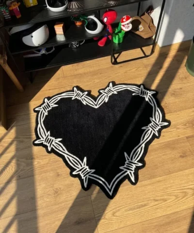Perspective view of the black and white Sacred Heart barbed wire rug styled in a sunlit room on wooden floors, placed next to a black shelving unit holding helmets and pop culture decor.