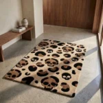 Perspective view of the Savage Skull Leopard rug placed on a smooth, light concrete floor in a bright, modern entryway, positioned next to a warm wooden bench and bathed in natural sunlight.