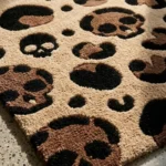 Angled close-up view of the Savage Skull Leopard rug, showcasing the plush depth and deeply carved black and brown leopard skull spots against the solid tan hand-tufted wool background.