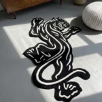 Perspective view of the Black Veil black and white traditional tattoo rose rug styled on a wooden floor in a living room next to a classic black fireplace, a potted plant, and a light grey leather sofa.