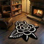 Wide perspective view of the Thornveil black and white rose rug styled in a warm library or den, surrounded by a wooden bookcase, a glowing floor lamp, a lit stone fireplace, and a classic leather wingback chair.