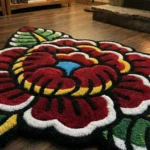 Close-up angled detail of the edge of the Traditional Peony rug, showcasing the plush, thick black wool border and a beautifully carved green leaf bathed in natural sunlight.