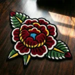 Top-down flat view of the Traditional Peony rug on a dark tile floor, showcasing its bold traditional tattoo flash design featuring a large red and pink peony with green leaves against a solid black base.