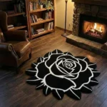 Wide perspective view of the Void Blossom black and white rose rug resting on dark hardwood floors in a warm den, surrounded by a wooden bookcase, a glowing floor lamp, a lit stone fireplace, and a brown leather armchair.