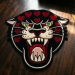 Top-down flat view of the Wild Heart Panther rug on a dark wood floor, featuring a hand-tufted traditional black panther head with vibrant red hearts across its forehead and cheeks.