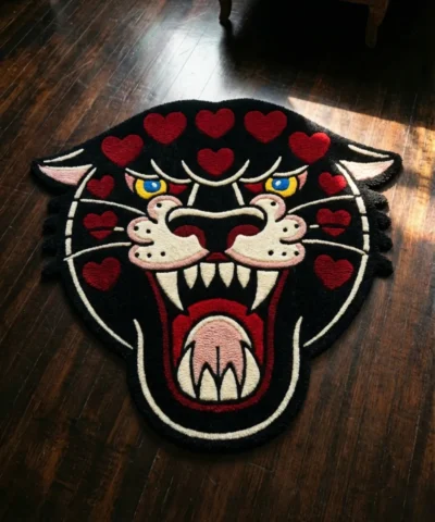 Top-down flat view of the Wild Heart Panther rug on a dark wood floor, featuring a hand-tufted traditional black panther head with vibrant red hearts across its forehead and cheeks.