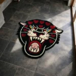 Angled perspective view of the Wild Heart Panther traditional tattoo rug styled on a dark slate tile floor in a sunlit modern entryway.