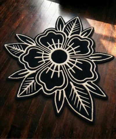 Full top-down product shot of the black and off-white Blackwork Flower rug featuring an American traditional tattoo style bold line design on dark hardwood flooring.