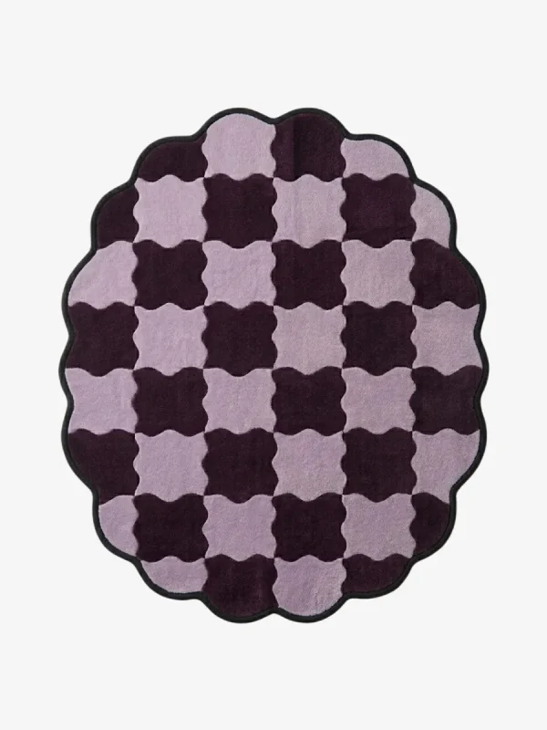 Top-down view of the round Amora Weave rug, featuring a whimsical wavy checkerboard pattern in alternating shades of light lilac and deep plum purple, framed by a continuous black scalloped border.