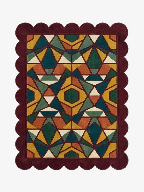 Top down view of the Autumn Prism rug featuring a complex geometric kaleidoscope pattern with faceted triangular shapes in rich autumn tones of ochre, rust, and forest green, finished with a deep burgundy scalloped border.