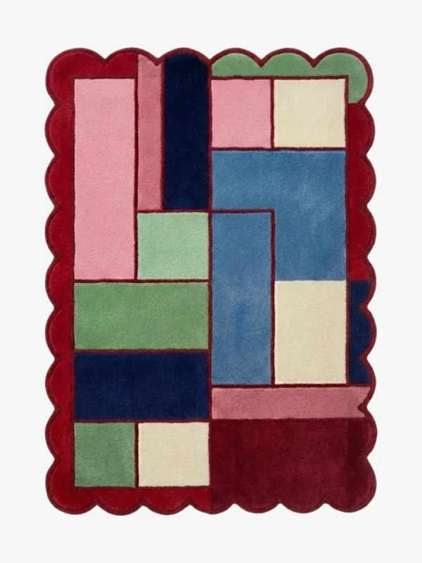 Top down view of the Canvas Mosaic rug featuring a vibrant, multi-colored geometric block design surrounded by a decorative red scalloped border.