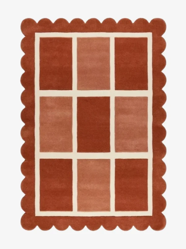Top-down view of the rectangular Canyon Panel rug featuring a cream windowpane grid with nine alternating color-blocked squares in shades of rust and peach, framed by a thick terracotta scalloped border.