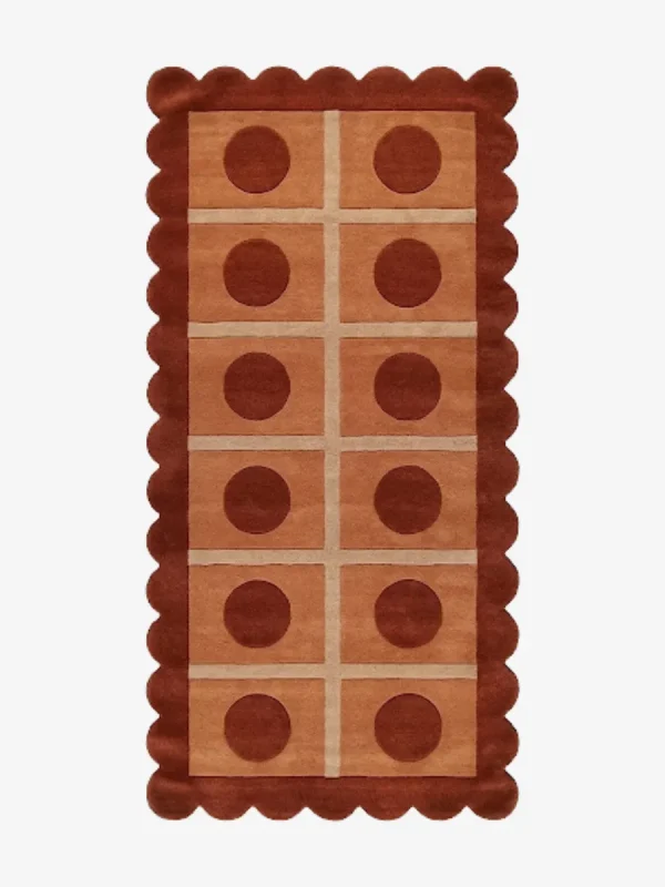 Top-down view of the rectangular Cocoa Ridge runner rug, featuring a retro-inspired grid of light peach squares containing dark cocoa brown circles, all framed by a thick terracotta scalloped border and intersecting cream lines.