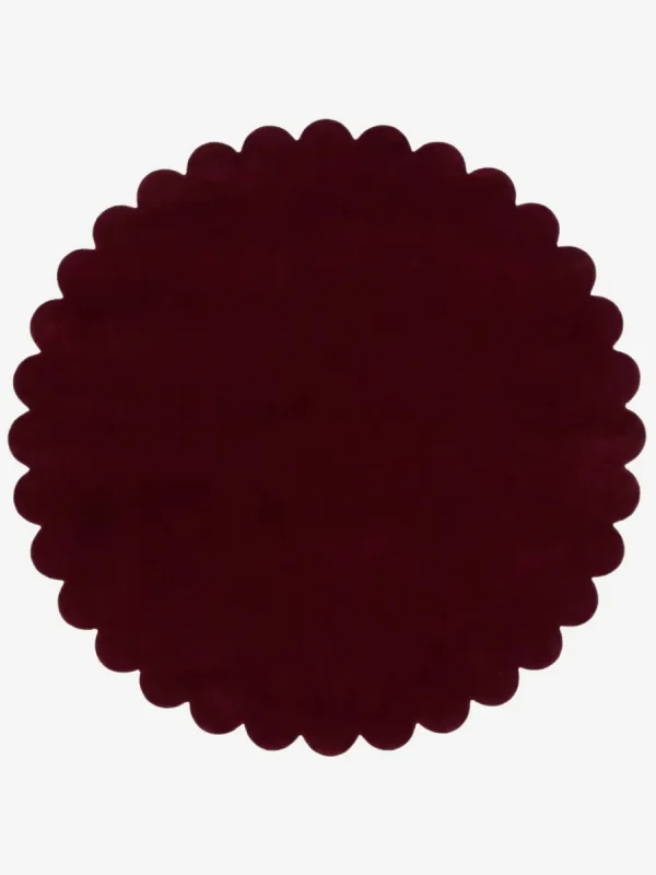 Top down view of the circular Crimson Aura deep red hand tufted wool rug on a white background showing the scalloped border.