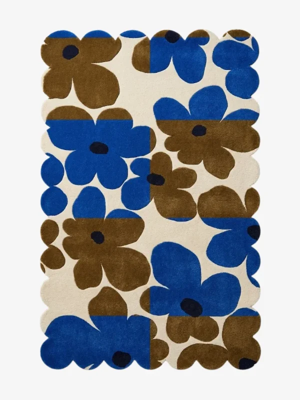 Top down view of the Earthen Dusk rug featuring a retro floral pattern with bold blue and brown flowers on a color blocked cream background with scalloped edges.