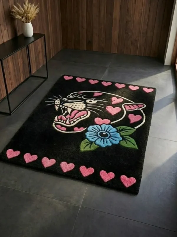Perspective view of the rectangular black Inkheart Panther rug styled on a dark slate tile floor in a modern entryway, bathed in bright natural sunlight next to a dark wood console table.