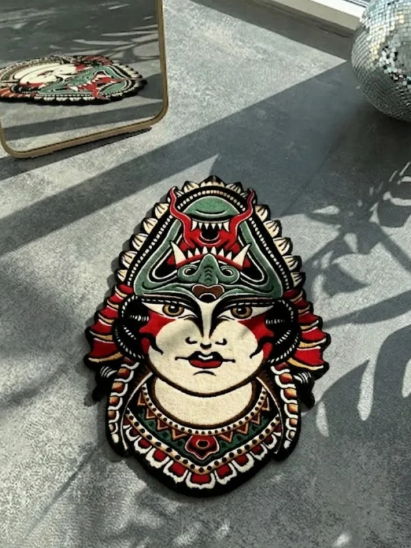 Top-down flat view of the die-cut Lady Face traditional tattoo rug, featuring a woman wearing a fierce green and red demon headdress, styled on a smooth concrete floor with striped sunlight shadows.