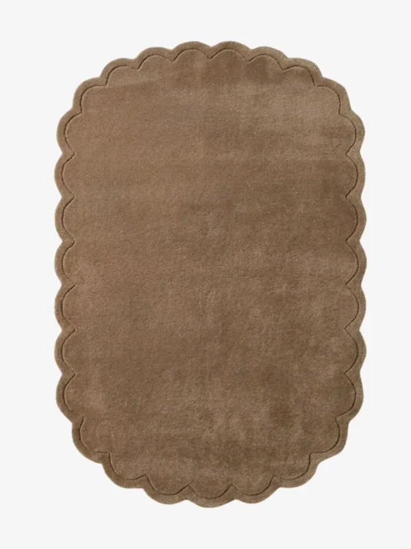 Top-down view of the rectangular Latte Halo rug, featuring a solid warm tan field and a continuous scalloped border accented by a delicate carved line detail.