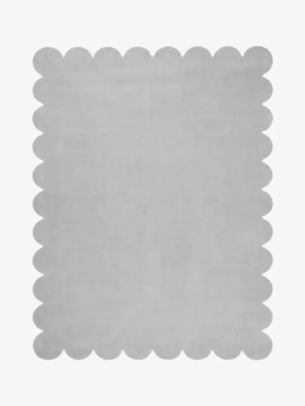 Top down flat lay of the Mistfall hand tufted rug featuring a calming solid silver gray color and decorative wavy edges isolated on a white background.