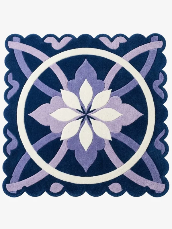 Top down view of the Moon Blossom rug featuring a central geometric flower motif in white and lavender on a deep navy blue background with scalloped edges.