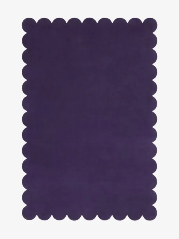 Top down flat lay of the Nightberry rug featuring a rich deep purple color and decorative scalloped borders isolated on a white background.