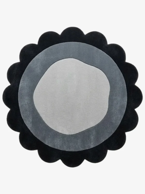 Top-down view of the circular Noctra Orb round rug, featuring a cream field with nested scalloped borders in soft black, gray, and a dark plum outer edge.