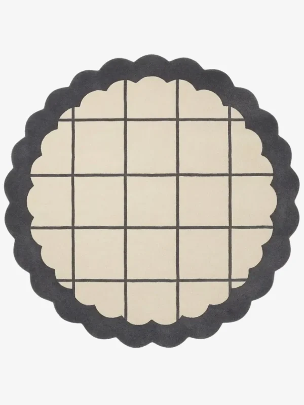 Top-down view of the circular Orbital Grid rug featuring a soft cream center with a classic dark grey windowpane grid, framed by a thick dark grey scalloped border.