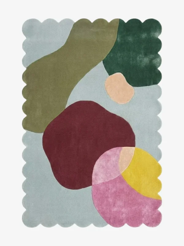 Top down view of the Pebble Parade rug against a white background, featuring large, organic, pebble-like abstract shapes in shades of olive green, dark green, deep burgundy, pink, yellow, and peach on a light blue background, framed by a continuous light blue scalloped border.