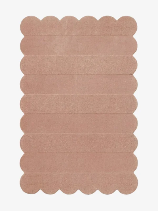 Top down view of the Petal Layers rug featuring a soft dusty pink color with horizontal carved textures and decorative scalloped edges.