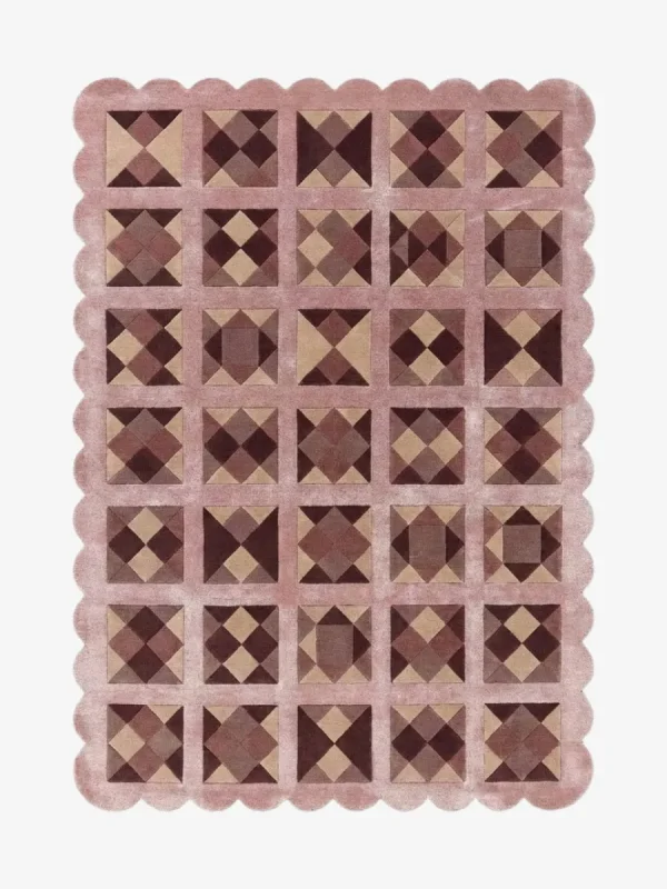 Top down view of the Rose Matrix rug against a white background, featuring a repeating patchwork pattern of geometric squares and diamonds in solid shades of soft pink, mauve, and deep burgundy, framed by a continuous pink scalloped border.