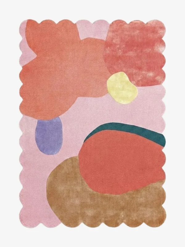 Top-down view of the Rose Riot rug against a white background, featuring large, organic abstract shapes in vibrant shades of coral, peach, yellow, periwinkle, teal, and warm brown on a soft pink background, framed by a continuous pink scalloped border.