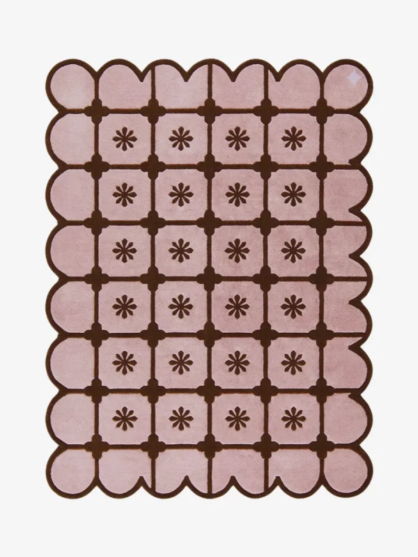 Top-down view of the rectangular Roselle Lattice rug, featuring a soft pink base with a dark brown grid pattern, a central floral motif in each square, and a matching continuous brown scalloped border.