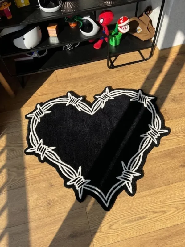 Perspective view of the black and white Sacred Heart barbed wire rug styled in a sunlit room on wooden floors, placed next to a black shelving unit holding helmets and pop culture decor.