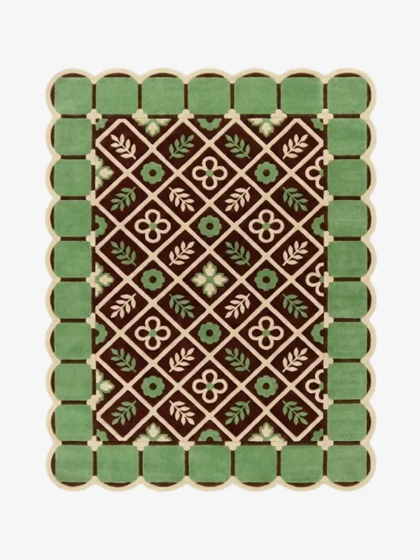 Top-down view of the Scroll Halo rug against a white background, featuring a dark brown center with a geometric diamond lattice pattern enclosing alternating cream floral motifs and light green leaf sprigs, surrounded by a light green square tile border and framed by a continuous cream scalloped edge.