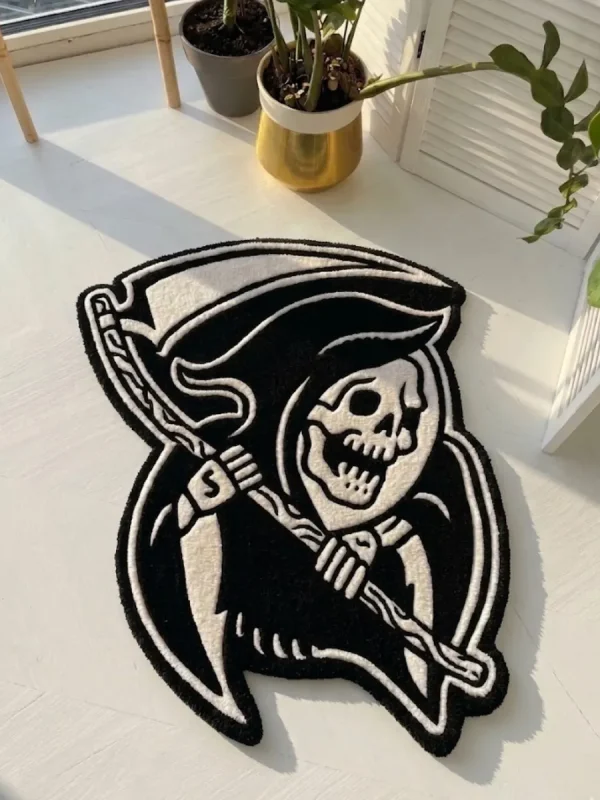 Angled perspective view of the Shadow Reaper black and white traditional tattoo flash rug resting on a white wooden floor, bathed in bright natural sunlight.