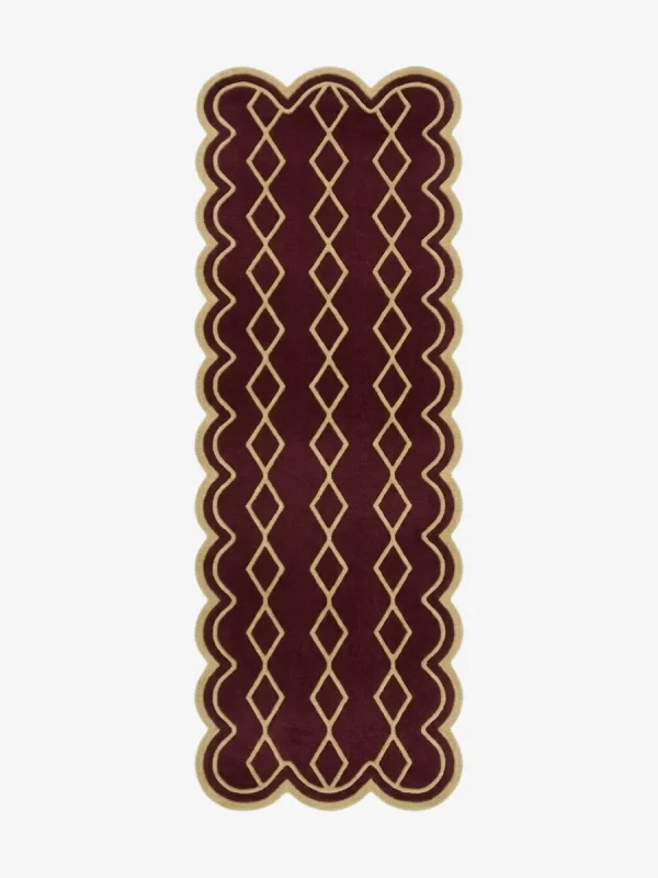 Top down view of the hand-tufted Solyvr Axis Runner Rug featuring a rich burgundy background, a gold geometric diamond pattern, and scalloped edges.