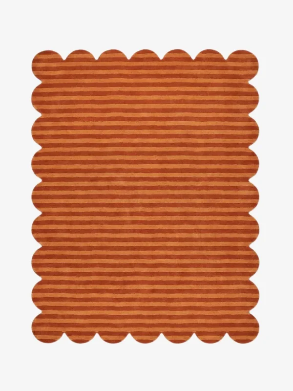 Top down view of the Sun Baked rug featuring warm rust and orange horizontal stripes with a carved texture and scalloped borders.