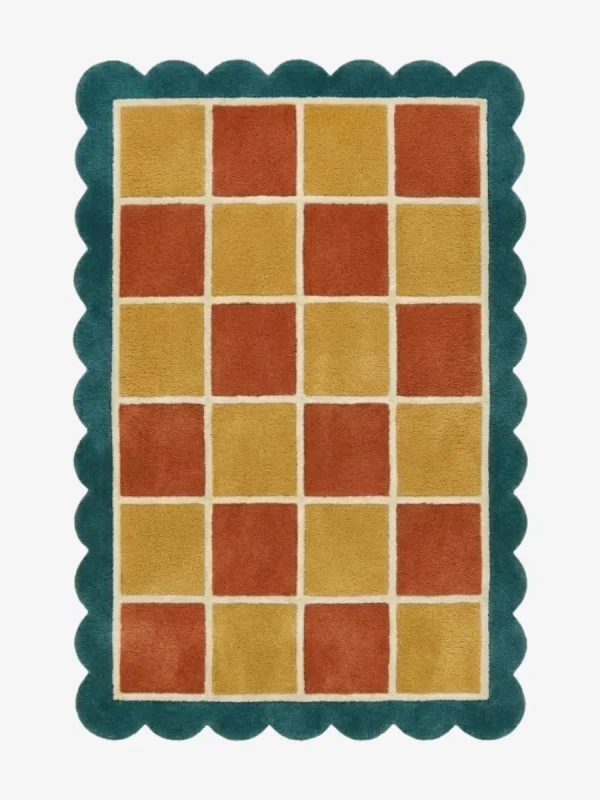 Top down view of the Sunbathe Quilt rug featuring a vibrant checkered pattern in rust orange, mustard yellow, and peach, framed by a cream line and a teal green scalloped border.