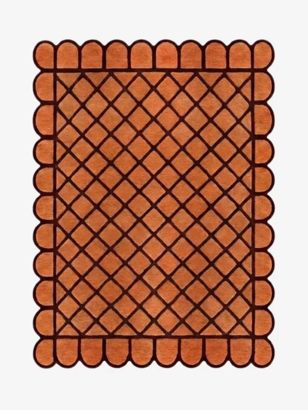 Top down view of the Terracotta Grid rug featuring a warm orange wool background with a bold dark brown square grid pattern and custom scalloped edges.