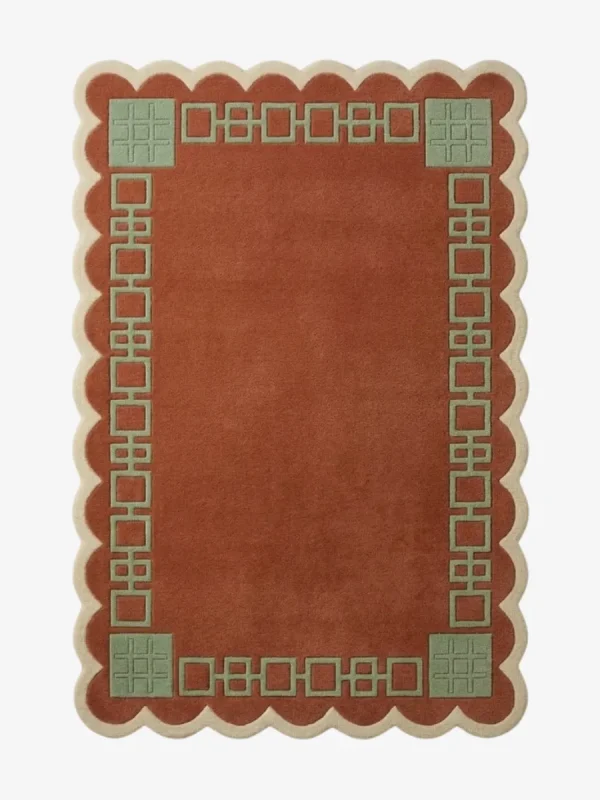 Top-down view of the rectangular Terrain Frame rug, featuring a solid rust orange center surrounded by a sage green geometric line border and framed by a continuous cream scalloped edge.