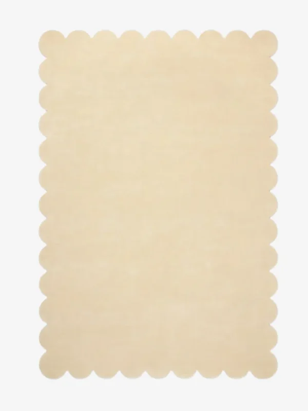 Top down view of the Vanilla Crest cream colored hand tufted wool rug on a white background showing the rectangular shape and scalloped edges.