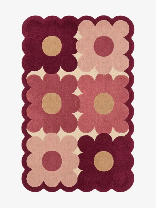 Top down view of the Velvet Garden rug featuring a playful grid pattern of large maroon and dusty pink flowers on a cream wool background, finished with custom scalloped edges.