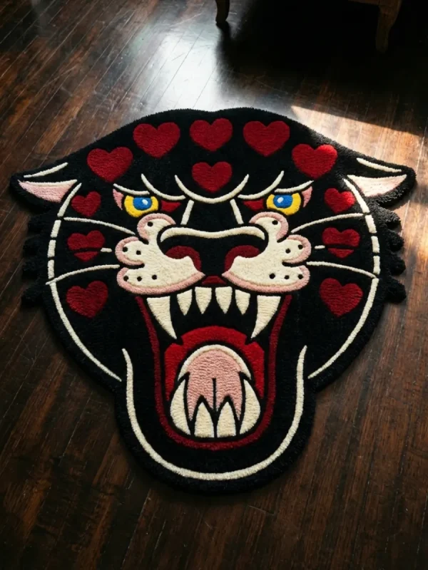 Top-down flat view of the Wild Heart Panther rug on a dark wood floor, featuring a hand-tufted traditional black panther head with vibrant red hearts across its forehead and cheeks.